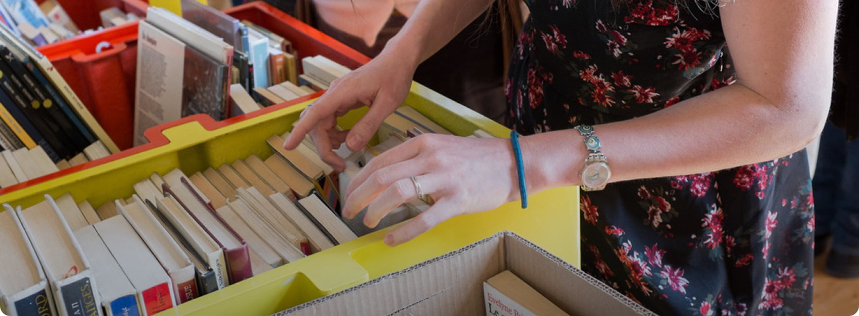 personne cherchant un livre dans un bac